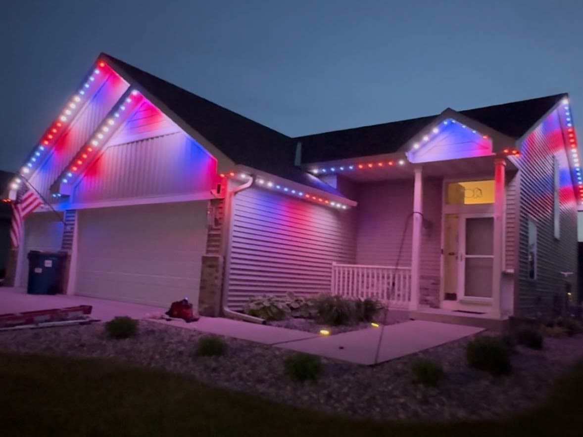 Single-story home at night with red, white, and blue lights following every gable peak and the front porch