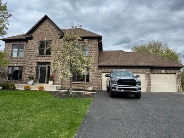 Two-story brick home in daylight, roofline and garage eaves unlit